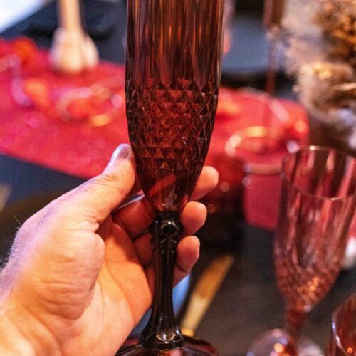 Main tenant une flûte réutilisable en plastique ambré, ambiance dîner à deux